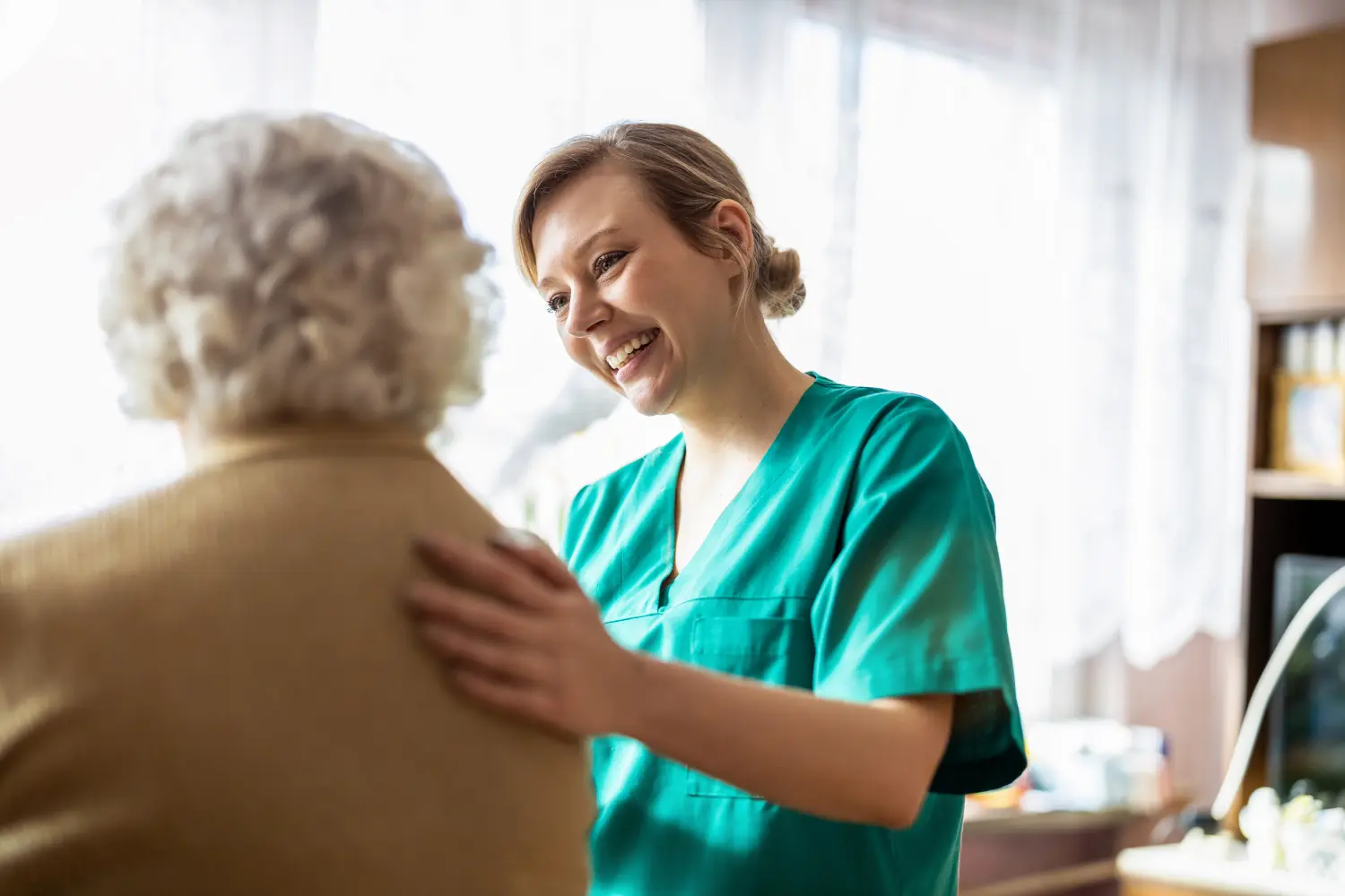 Freundliche Krankenschwester unterstützt eine ältere Dame